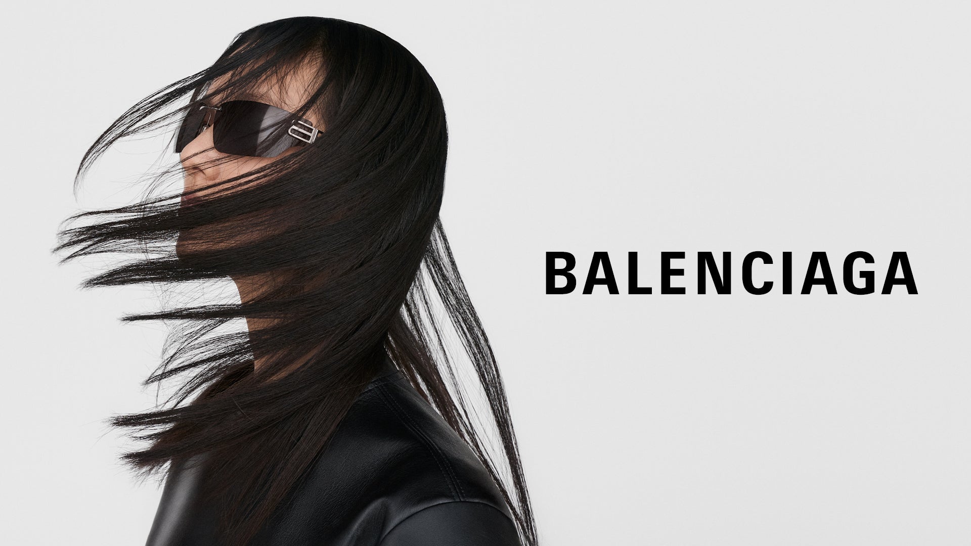 Person with long black hair wearing sunglasses and a black outfit, with 'BALENCIAGA' logo.