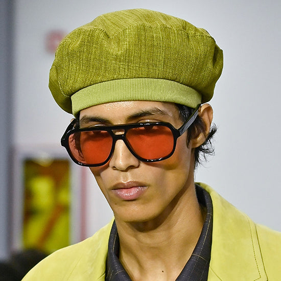 Male model on the runway wearing Paul Smith black square sunglasses with orange lenses and an olive green beret hat - Giarre.com Collection